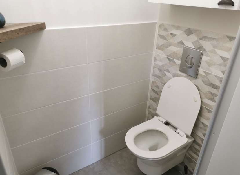 WC suspendu avec plaque de commande chromée dans des toilettes rénovées